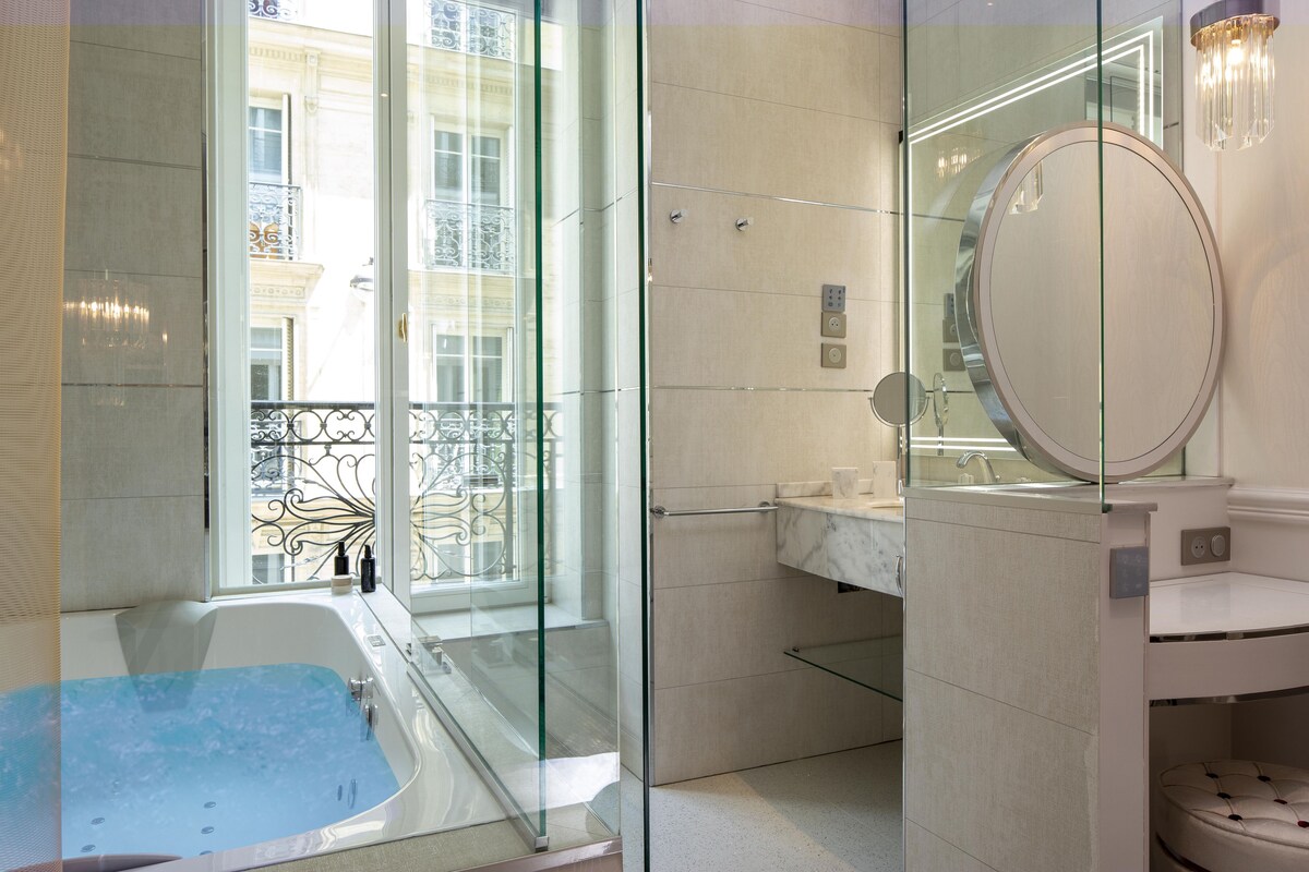 A modern bathroom with a glass-enclosed shower, a bathtub, and a vanity with a mirror.