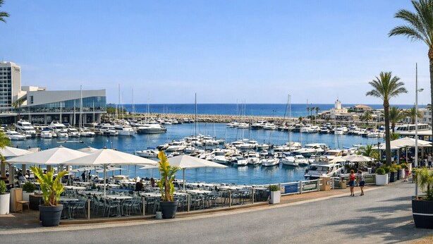 A marina with numerous boats, outdoor seating, and a building with a modern design. - T2 Porto Marina, a 4 min. Marina Vilamoura (Quarteira)