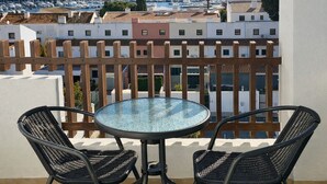 A balcony with a round glass table and two wicker chairs, overlooking a marina with boats and buildings. - T2 Porto Marina, a 4 min. Marina Vilamoura (Quarteira)