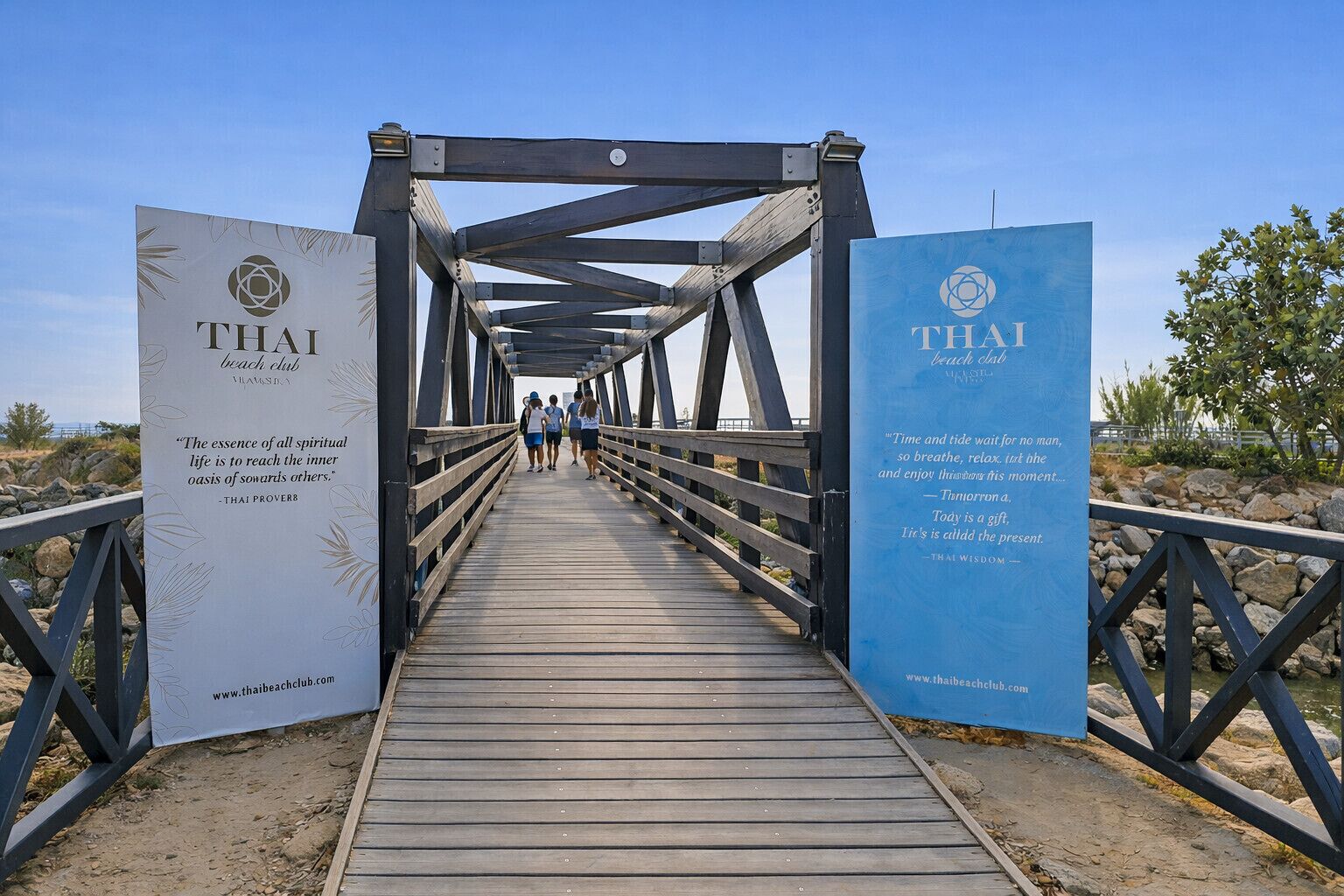 Un puente peatonal de madera con barandillas que conduce a una zona de playa.
