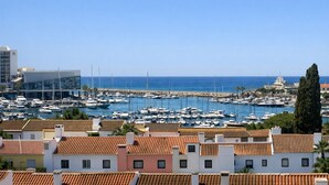 A marina with boats, a clear blue sky, and buildings with red-tiled roofs. - T2 Porto Marina, a 4 min. Marina Vilamoura (Quarteira)