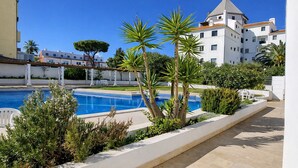 A swimming pool surrounded by greenery, a white building with a dome, and a clear blue sky. - T2 Porto Marina, a 4 min. Marina Vilamoura (Quarteira)