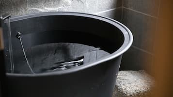 Una vasca da bagno con un rubinetto e una doccetta, su uno sfondo di piastrelle.