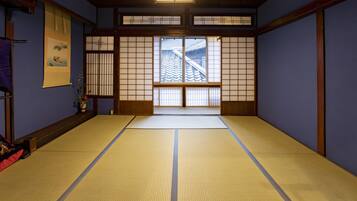 A traditional Japanese room with tatami flooring, shoji screens, and a view of a traditional building outside.