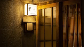 Entrada de um edifício tradicional japonês, com uma placa indicando o nome 'Kanazawa machiya Kenroku'.