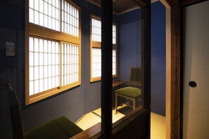 Une pièce dotée d’une porte coulissante de style japonais traditionnel, d’un fauteuil rembourré de couleur verte et d’une table en bois.