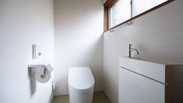 A small, modern bathroom with a toilet, a sink, and a window above the sink.