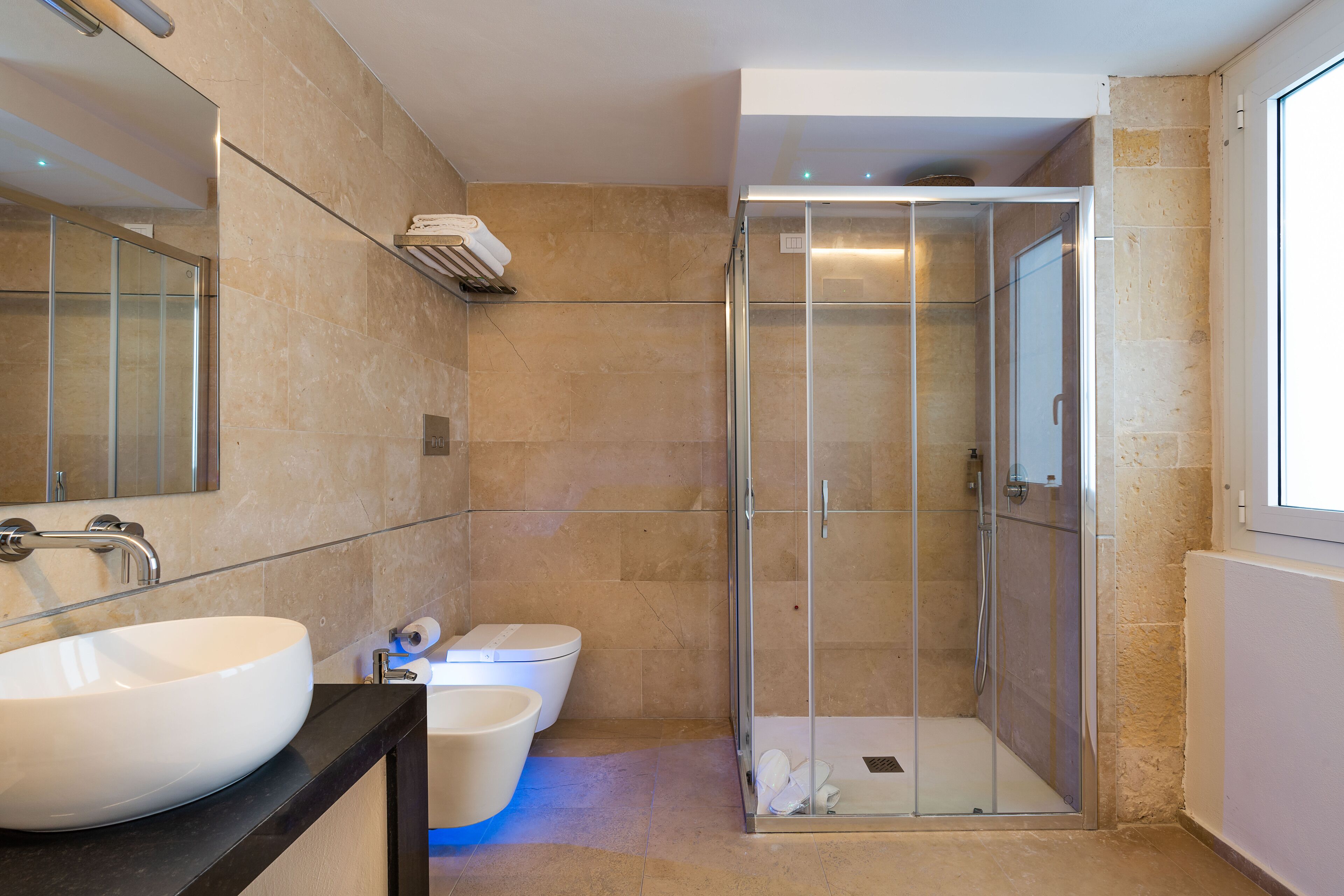 Ein modernes Badezimmer mit einem großen weißen Waschbecken, einer Toilette und einer Duschkabine.