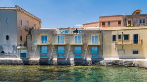 A waterfront building with multiple balconies and clear water in front. - Re Dionisio Luxury Suites (Syracuse)