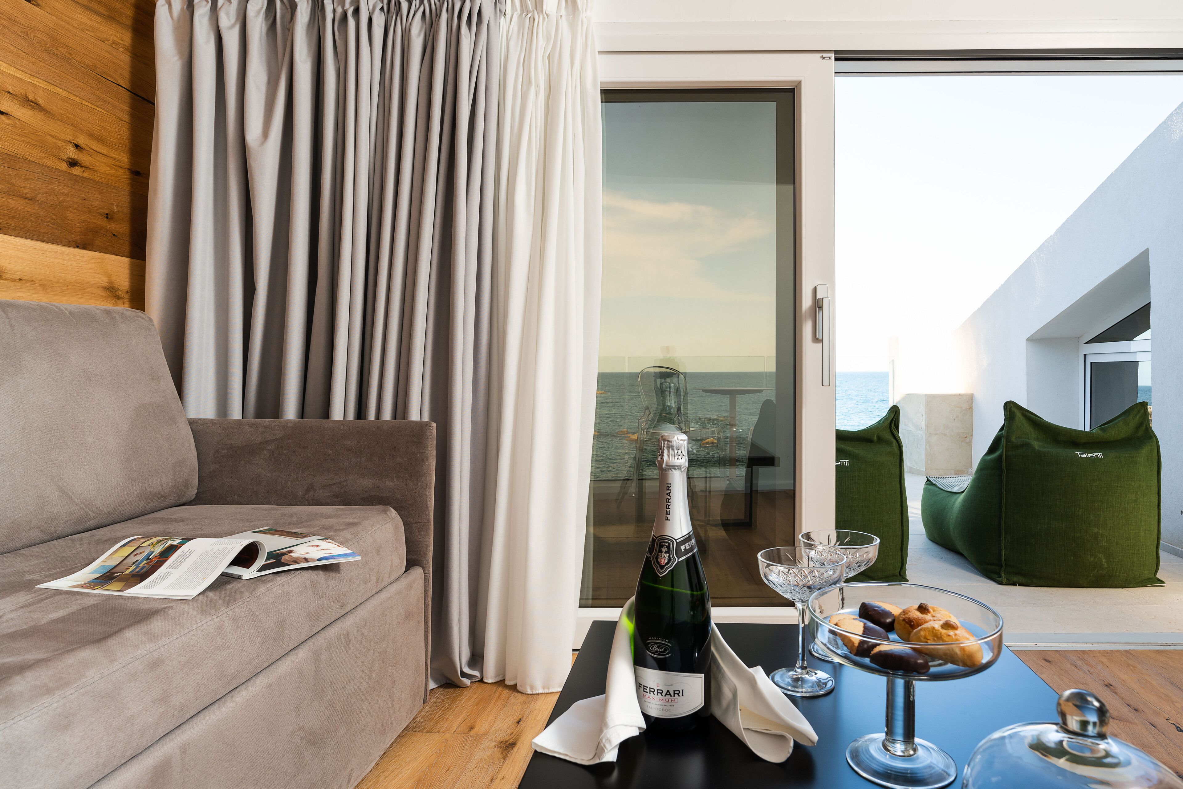 Ein modernes Zimmer mit einer Couch, einem Tisch mit einer Champagnerflasche, einem Glas und einer Schale süße Leckereien.