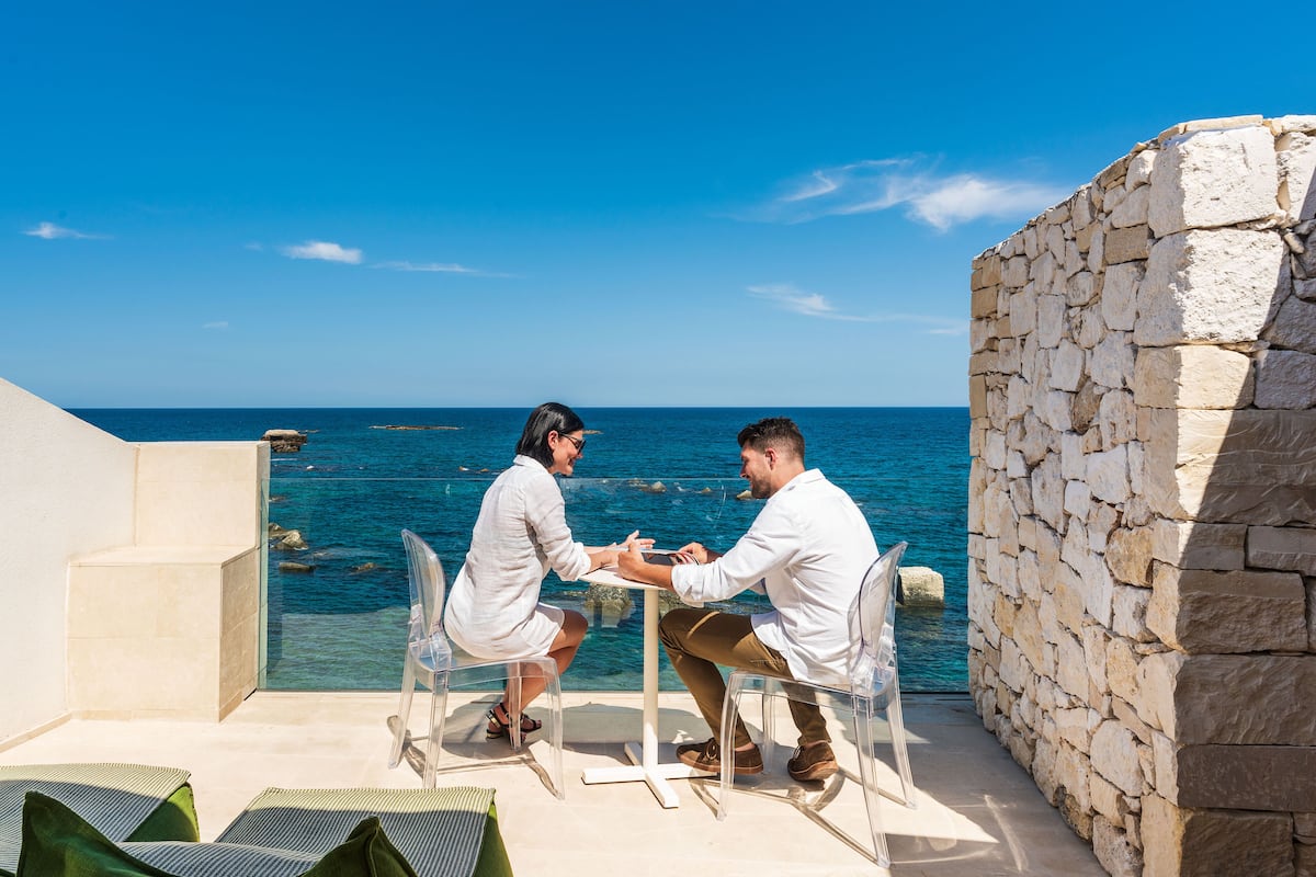 Two people seated at a table with a view of the sea.