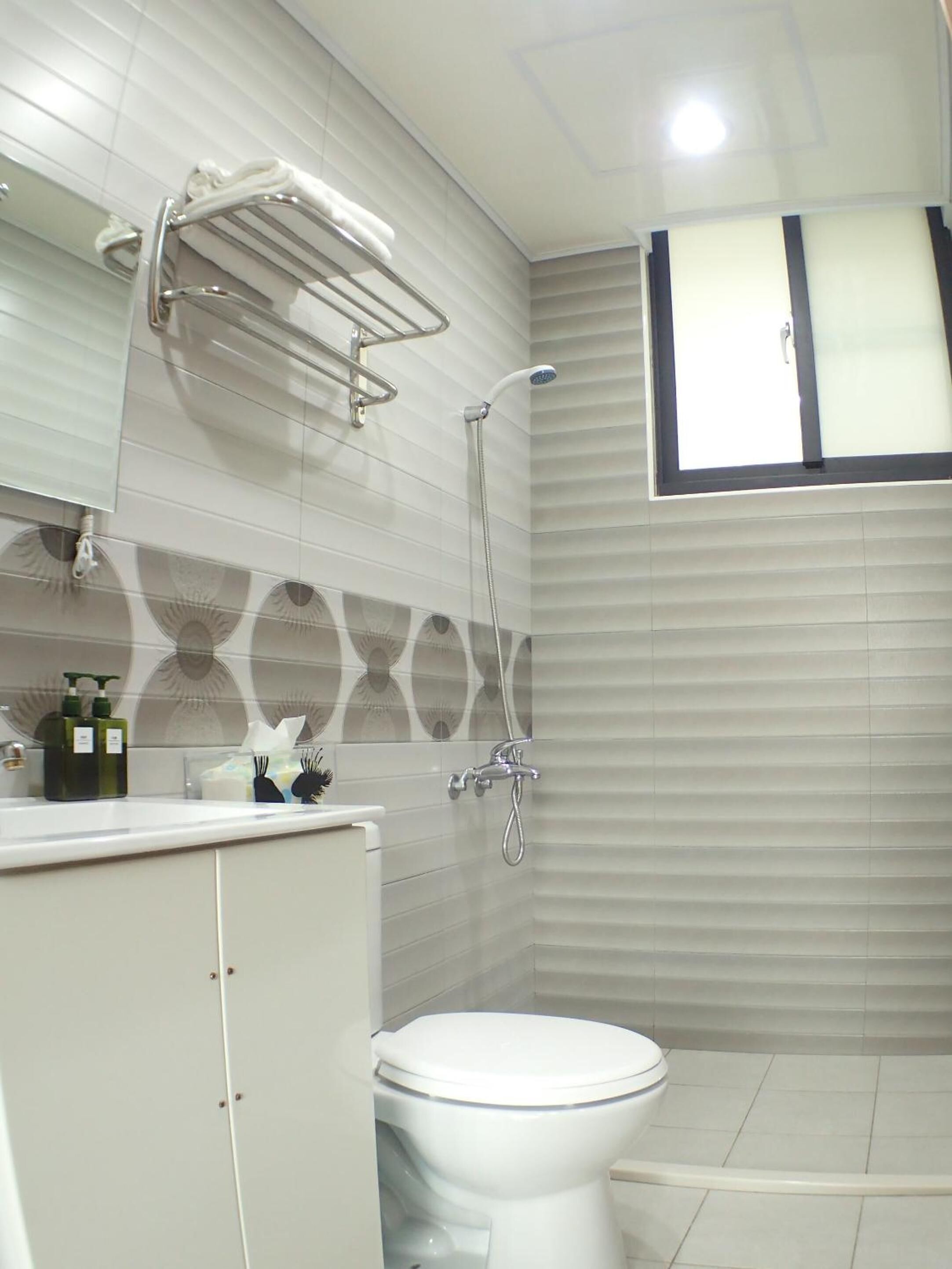 A bathroom with a toilet, a shower, and a vanity with a mirror.