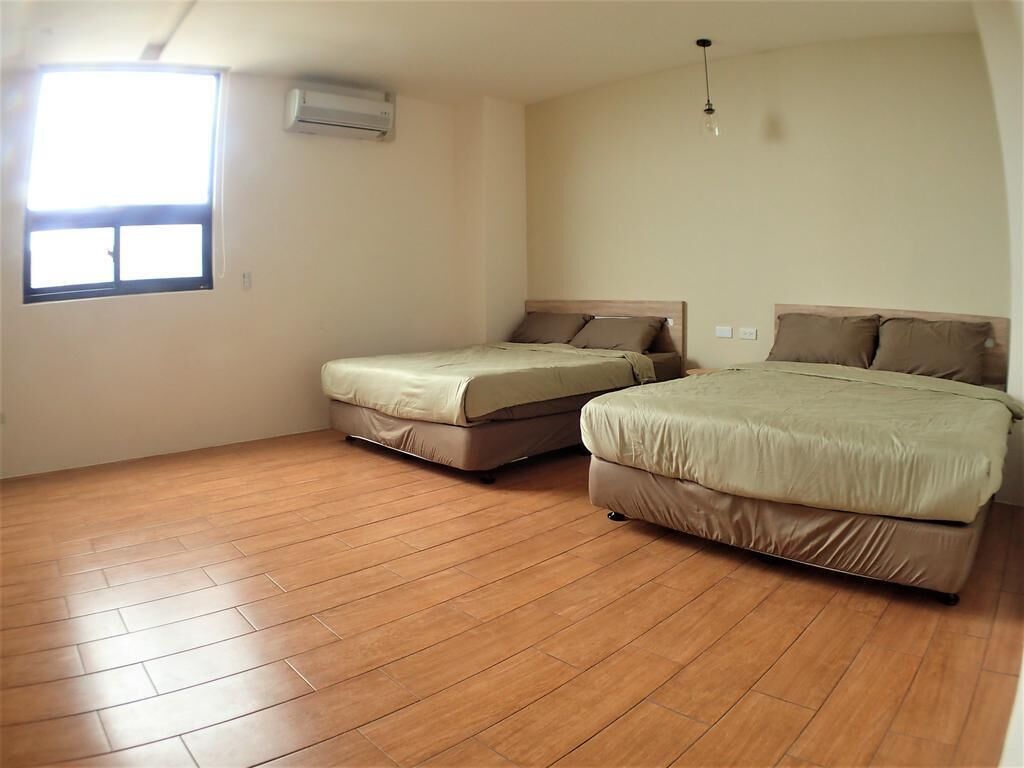 Habitación con dos camas, una ventana y aire acondicionado.