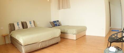 A bedroom with a large bed, a smaller bed, a chair, and a table with a lamp.