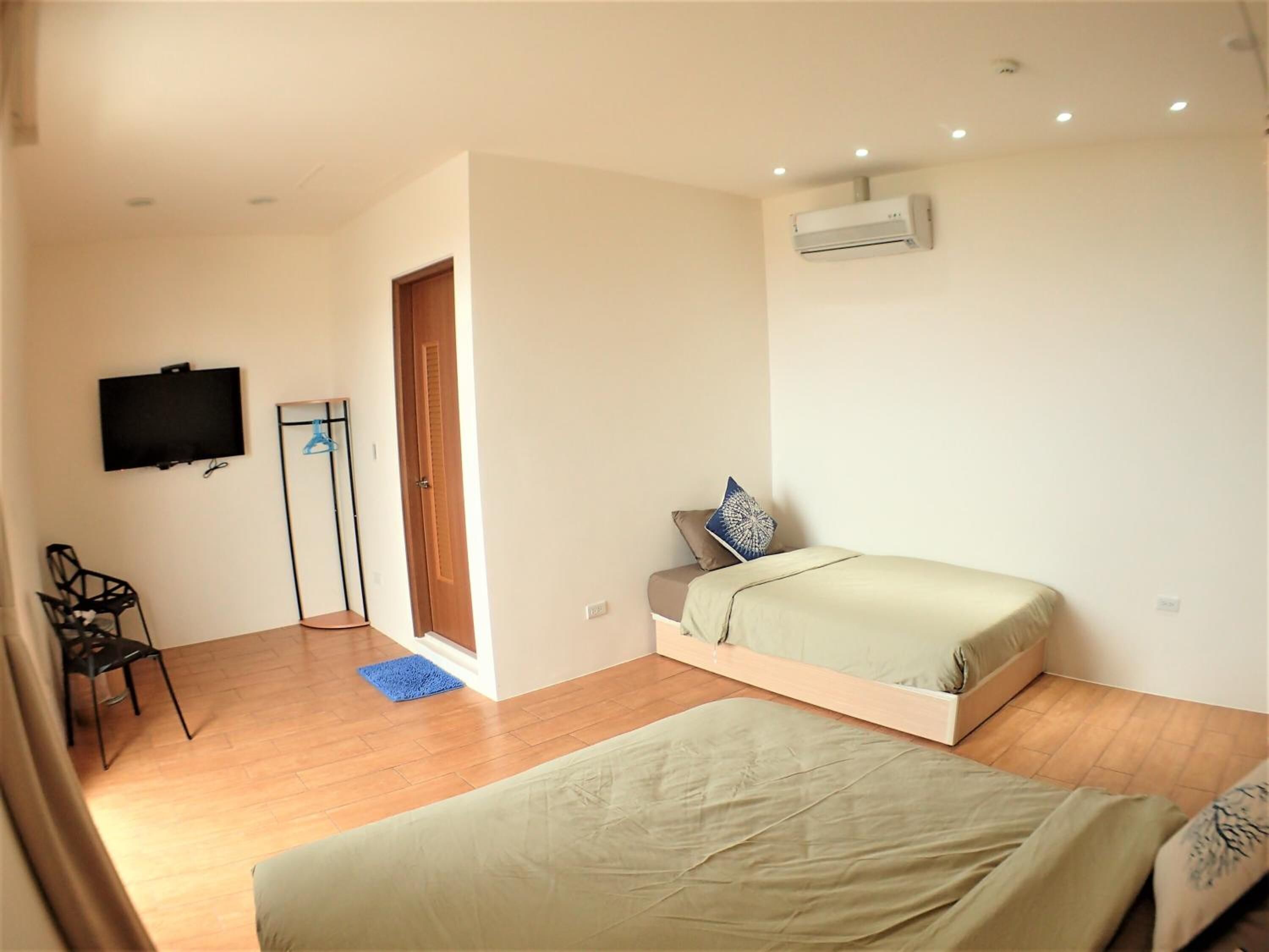 A bedroom with a bed, a chair, a TV, and an air conditioning unit.