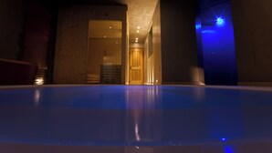 Piscina com interior de madeira, uma porta que dá para outro espaço e um luminário azul.