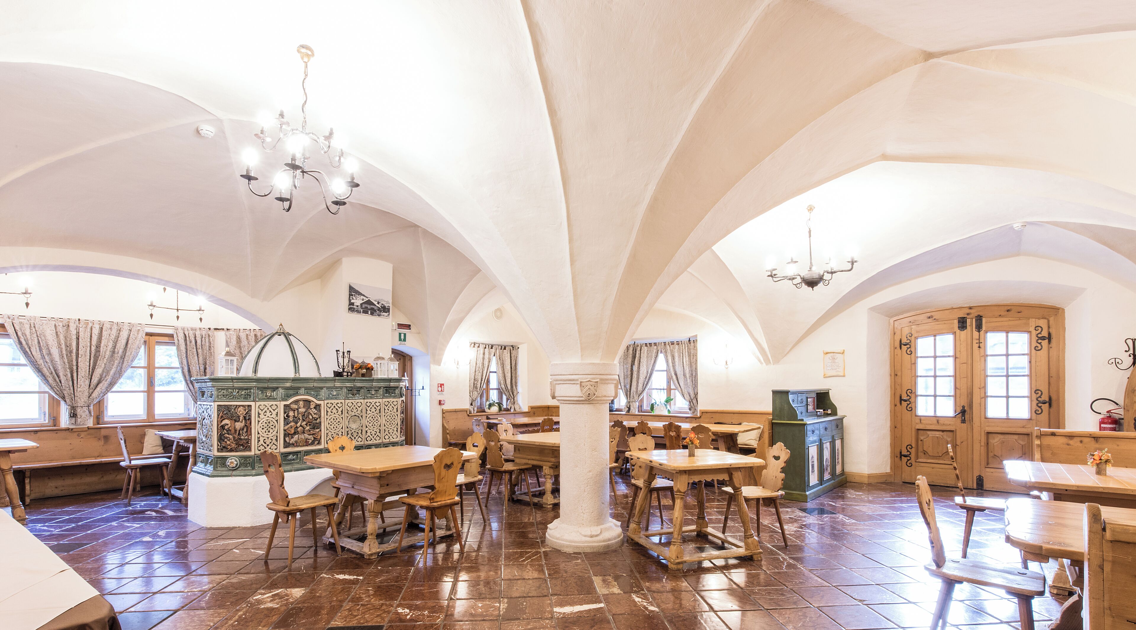 A spacious hall with high ceilings, wooden tables and chairs, and a central column.