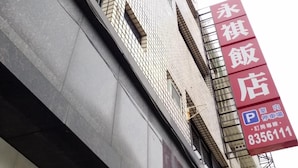 A building with a tiled facade and a large red sign indicating a restaurant.