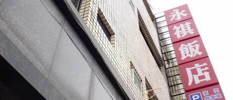 Un bâtiment à la façade recouverte de carreaux et portant une grande enseigne rouge indiquant qu’il s’agit d’un restaurant.