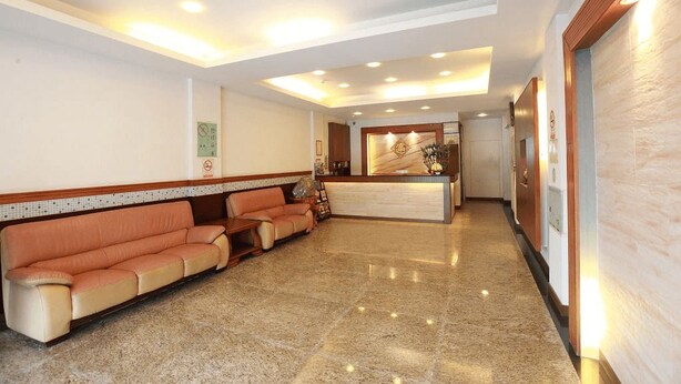 A hotel lobby with a reception desk, a sofa area, and a polished marble floor.