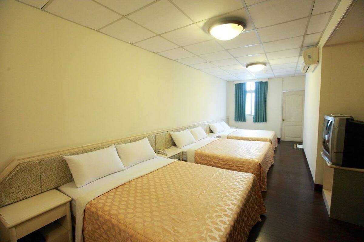Une chambre d’hôtel avec deux lits, une télévision et un bureau.