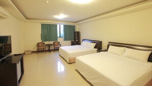 A hotel room with two beds, a desk with a chair, a TV, and a window with curtains.
