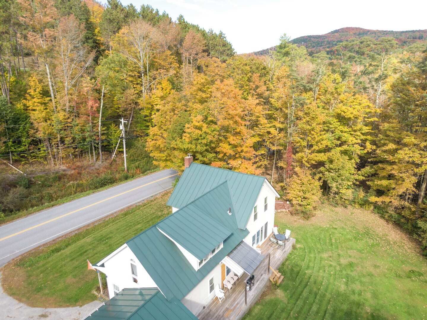 A house with a green roof, surrounded by a well-maintained lawn and a road.