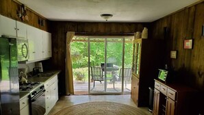 A kitchen with a gas stove, cabinets, and a large sliding glass door leading to a patio.