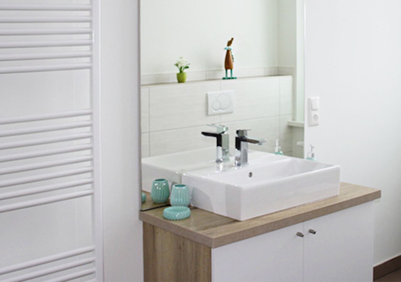 Een badkamer met een wit wastafel, een houten aanrechtblad en een spiegel erboven.