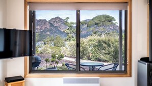 Ein Zimmer mit großem Fenster und Blick auf Berge und Bäume.