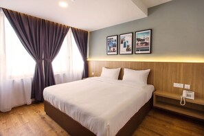 A hotel room with a large bed, wooden headboard, a bedside telephone, and a wall-mounted light fixture. - Hotel Insuna (Johor Bahru)