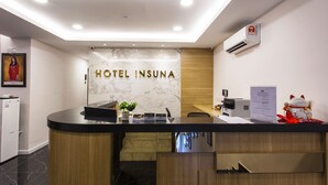A hotel reception desk with a marble wall, a wooden panel, and a sign that reads "HOTEL INSUNA". - Hotel Insuna (Johor Bahru)