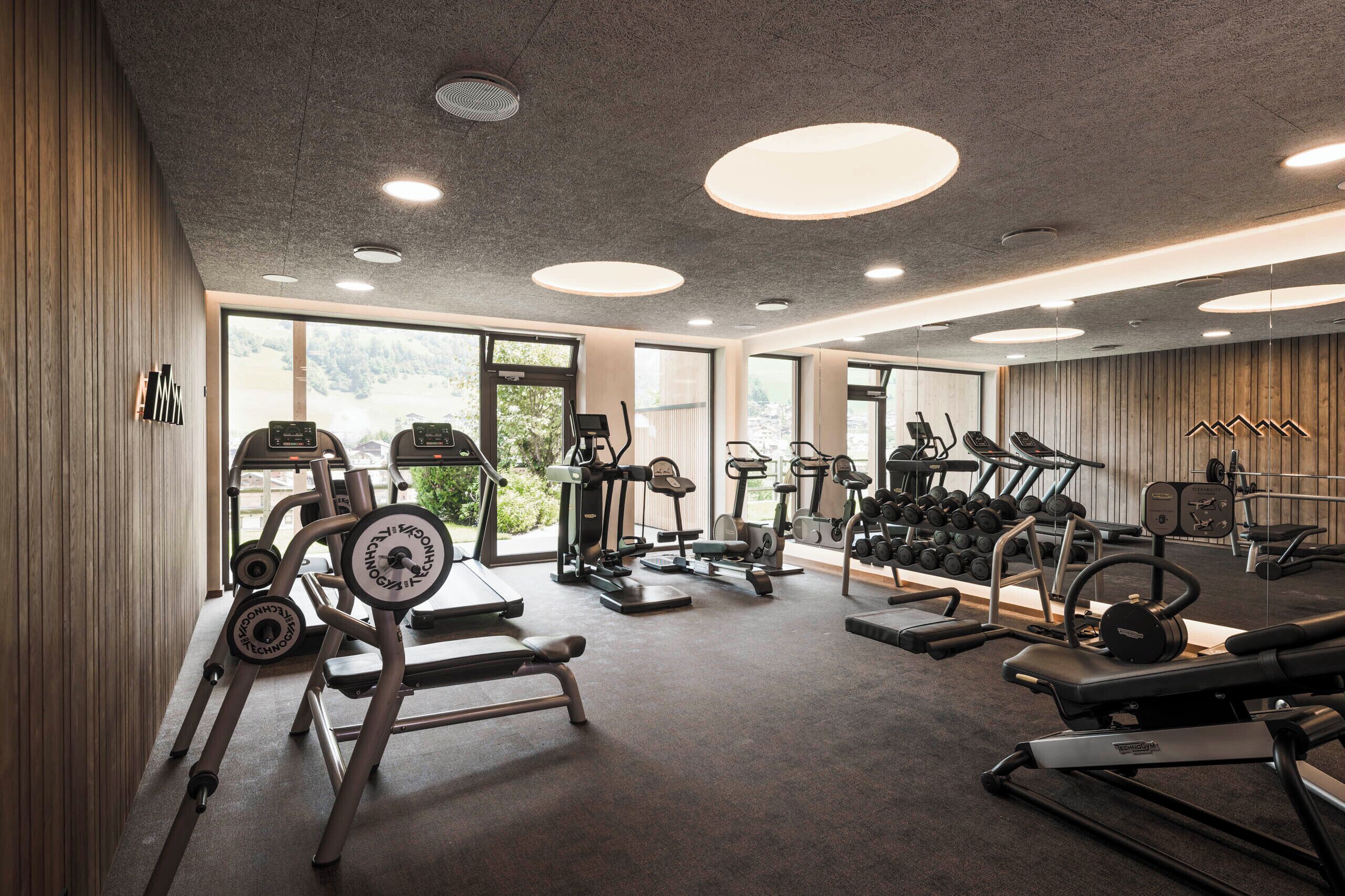Un gimnasio moderno con máquinas de cardio, pesas libres y una variedad de equipamiento de ejercicio.