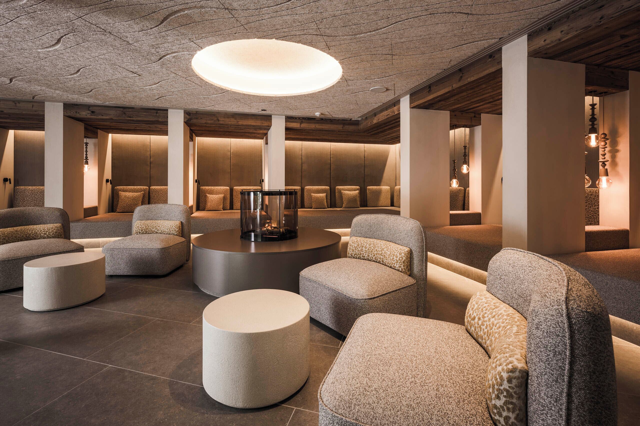 A modern spa area with multiple seating options, a central light fixture, and a stone ceiling.