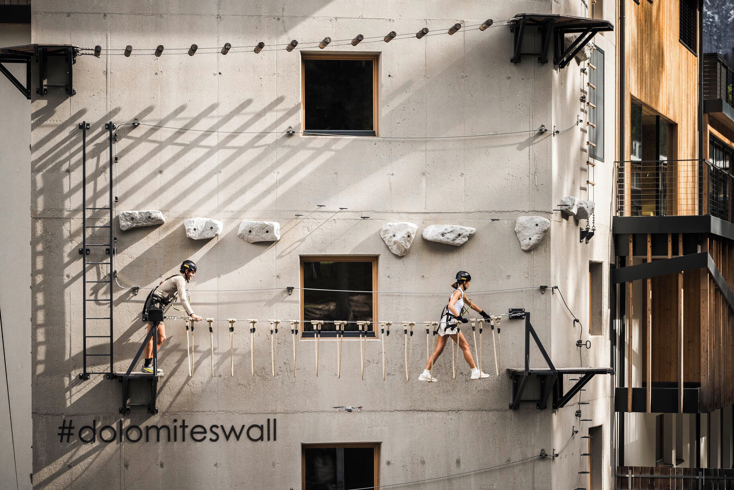 Un edificio con una pared de escalada, una escalera y un hashtag en la pared.