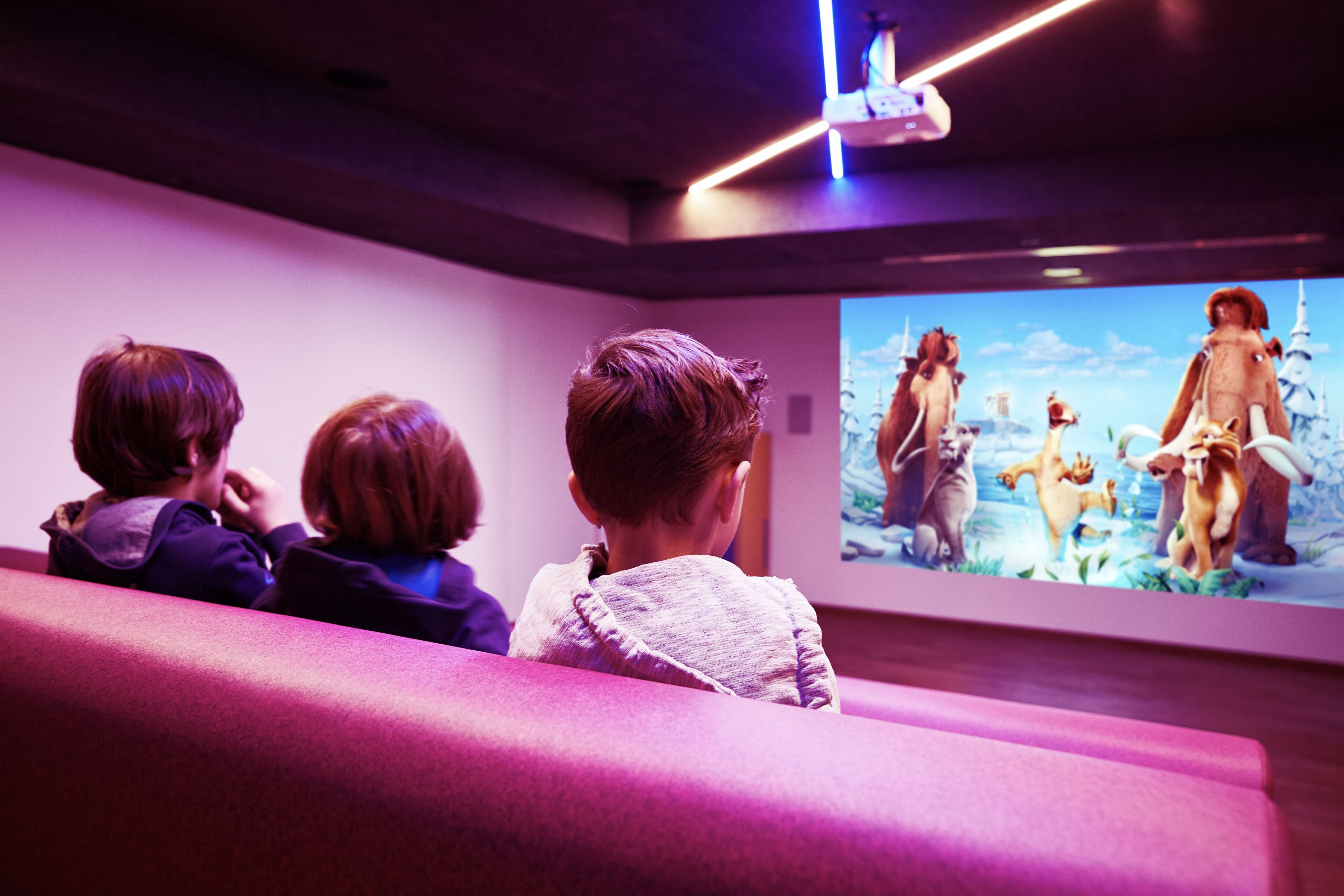 A group of people watching a projected image on a wall in a room with a modern design.