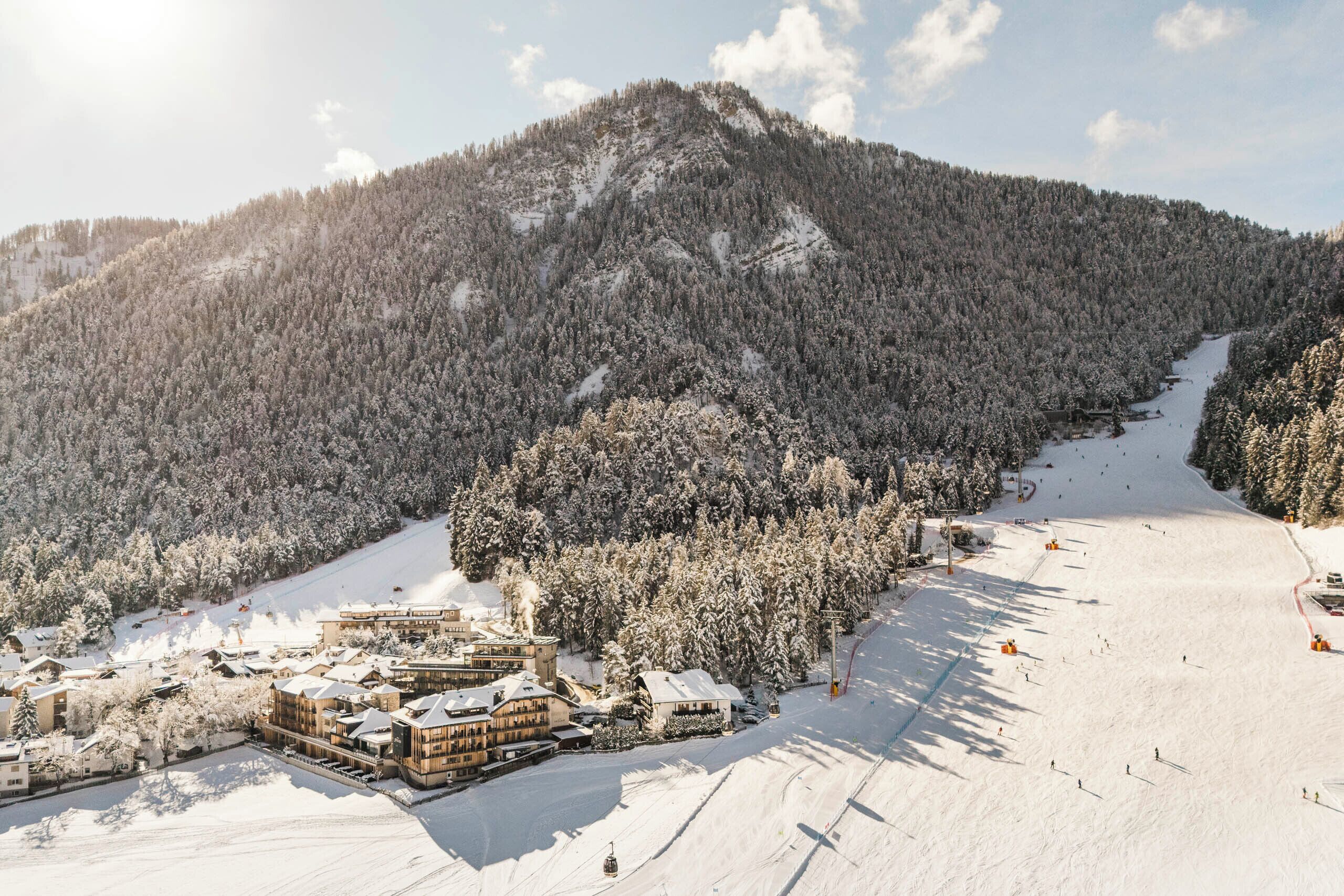 A snow-covered mountain with a ski resort, including buildings and a ski lift.