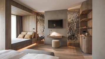 A modern bedroom with a large bed, a TV mounted on the wall, and a wooden cabinet.