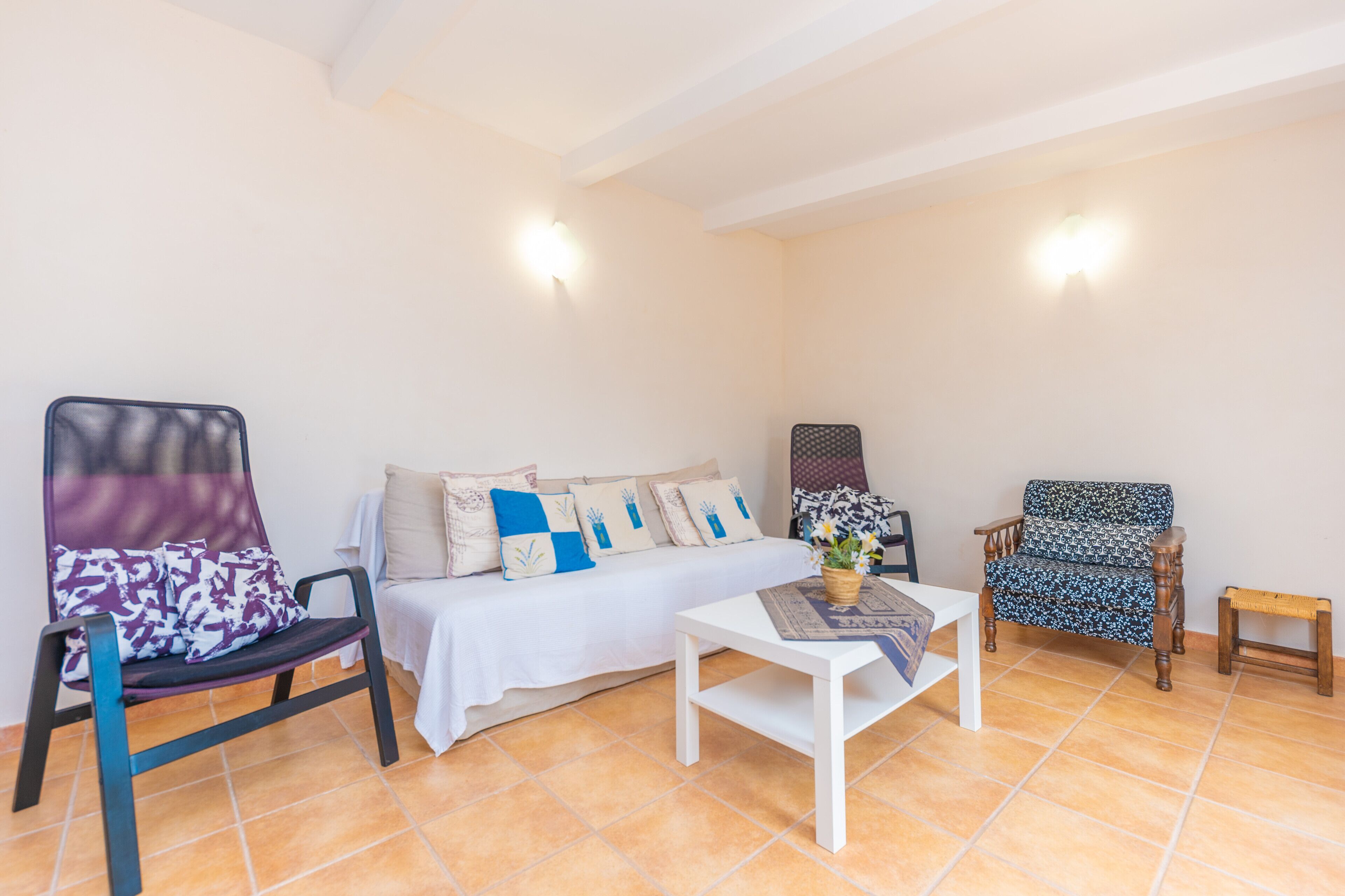 A room with a bed, two chairs, a small table, and a bench.
