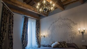 A bedroom with a large ornate headboard, a chandelier, and patterned curtains. - San Marco Luxury property with terraces. Muneghe (Venezia)