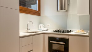A compact kitchen with a window, stainless steel range hood, built-in oven, and white cabinetry. - San Marco Luxury property with terraces. Muneghe (Venezia)