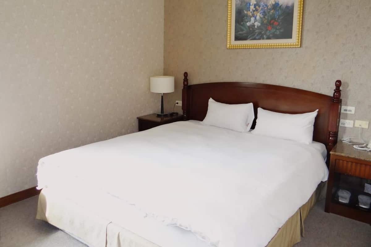 A neatly made bed with white linens in a hotel room.