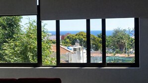 Una habitación con un ventanal que ofrece vistas a una zona residencial y al mar.