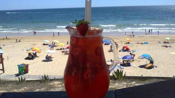 Escena de playa con vista despejada del océano y una sombrilla.