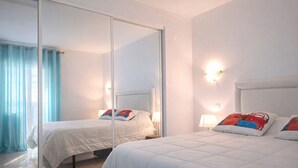 Habitación de hotel con dos camas, un espejo grande y vista al mar.