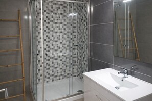 Une salle de bain avec une douche, un lavabo et un miroir.