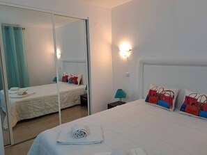 Comfortable accommodations feature a bed with a white duvet, a bedside table, and a mirrored closet.