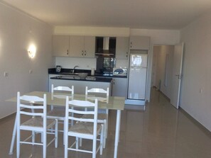 Enjoy meals at the dining table with four chairs in this kitchen, equipped with an oven, microwave, and refrigerator.