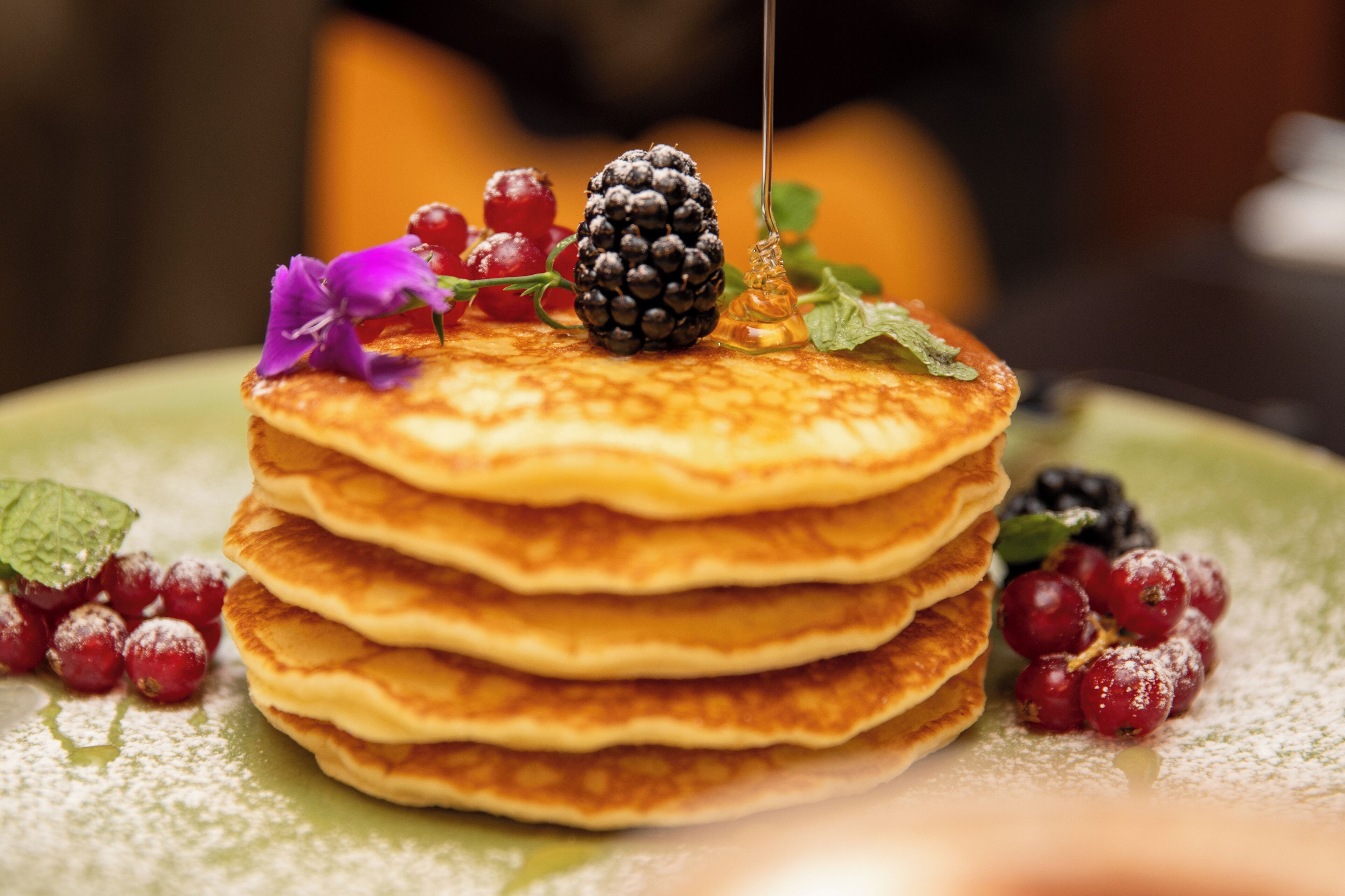 Una pila di pancake con frutti di bosco e sciroppo su un piatto.