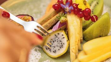 Une assiette de fruits variés, notamment des kiwis, des mangues et des baies.